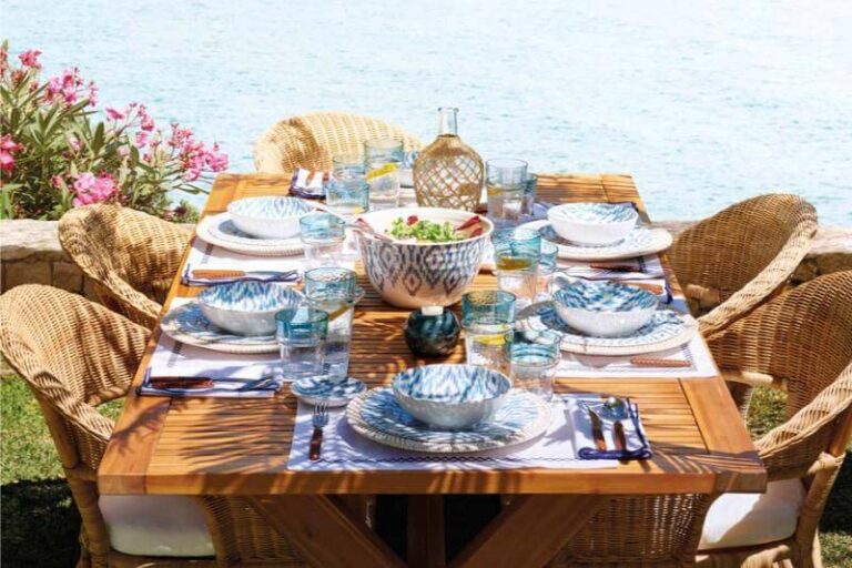 Mesa preparada para comer en el jardín con vistas al mar.