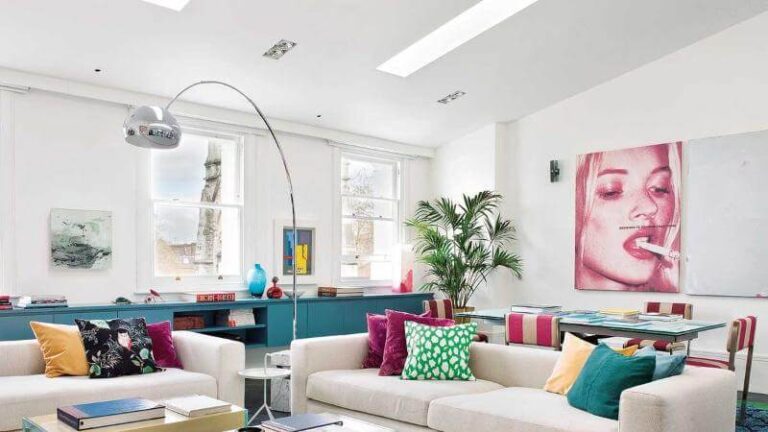 Sala de estar luminosa con sofá colorido, mesa de centro de madera, silla ergonómica y escritorio ajustable