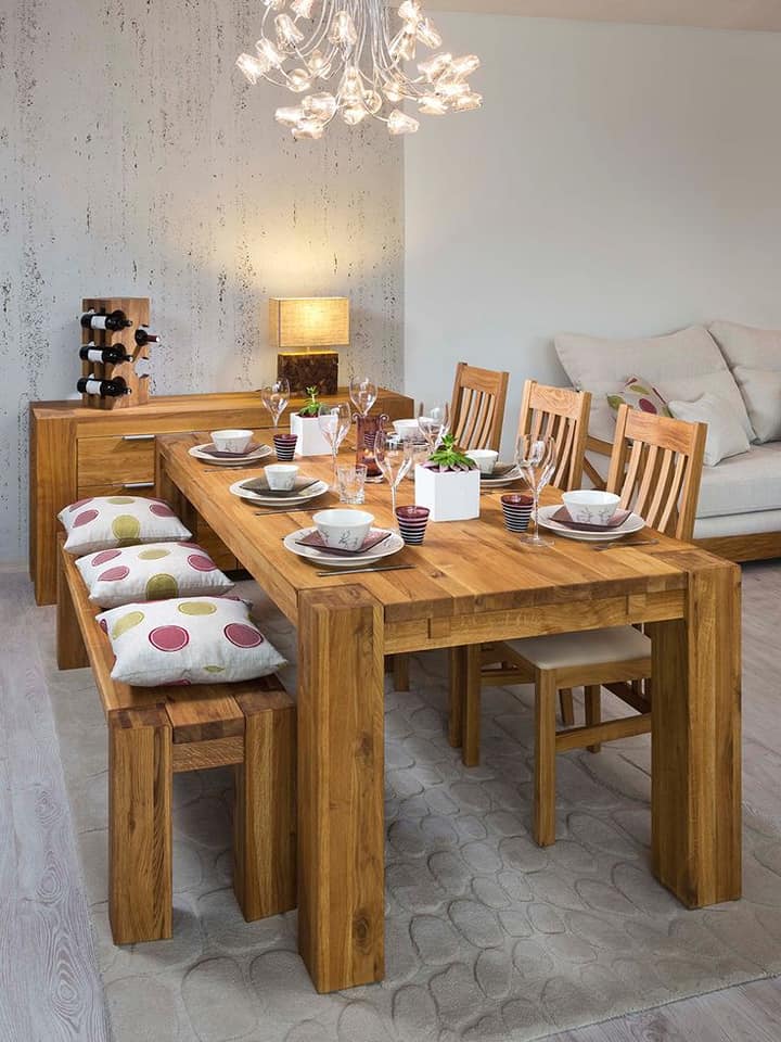 Comedor rústico con mesa de madera, sillas con cojines en tonos tierra y centro de mesa con elementos naturales.