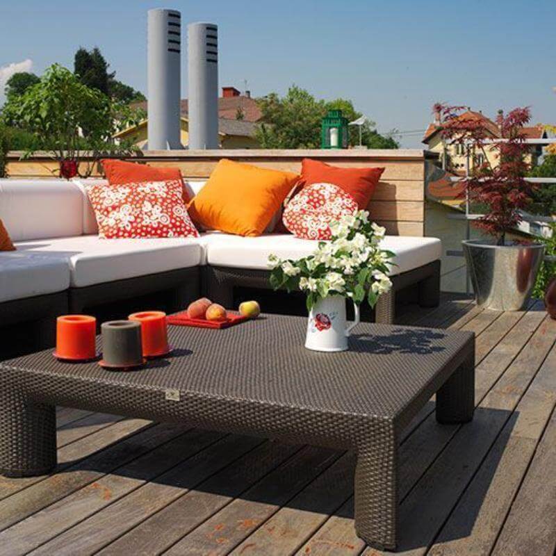 Una terraza en nuestra casa preparada para el verano con muebles de jardín, cojines coloridos y varias plantas en macetas.