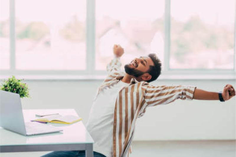 Persona tomando un descanso y estirándose en su espacio de trabajo en casa