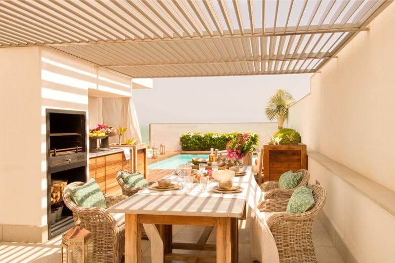 Una terraza con una barbacoa, mesa de comedor y sillas cómodas.
