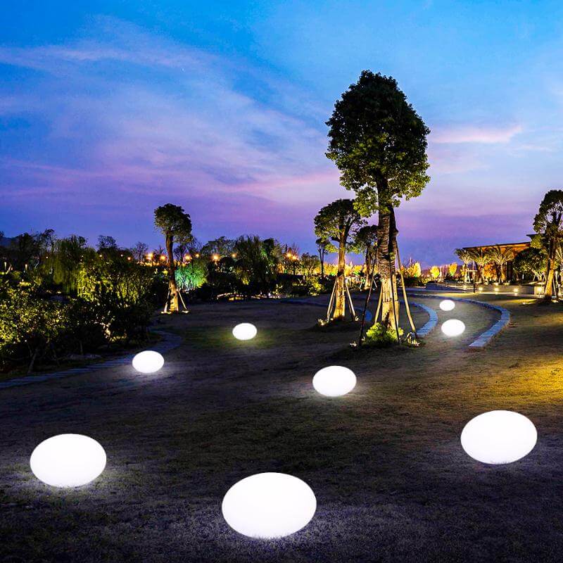 Para Vivir el Verano al Máximo. Luces solares decorativas encendidas, dispuestas en un jardín al anochecer, proporcionando una iluminación suave y ambiental.