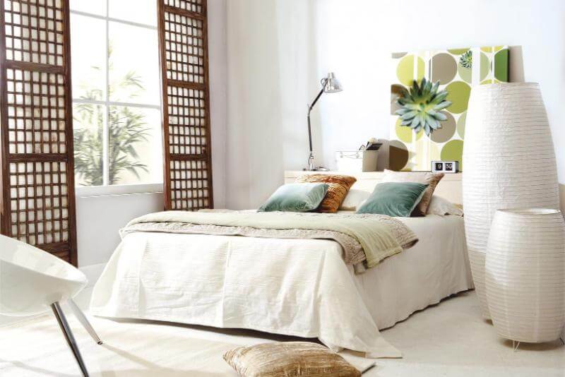 Un dormitorio con ropa de cama blanca y detalles en fibras naturales.