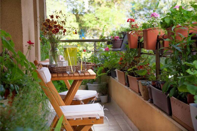 Pequeño balcón decorado con muebles compactos y plantas en macetas, aprovechando al máximo el espacio reducido.