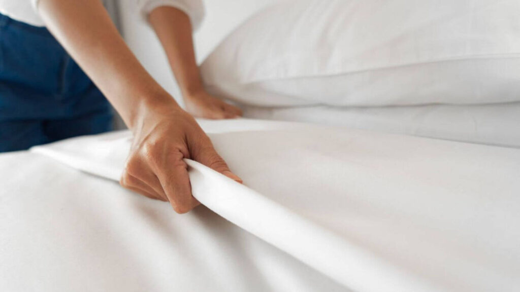 Estirando la sábana para lograr una cama impecable y cómoda