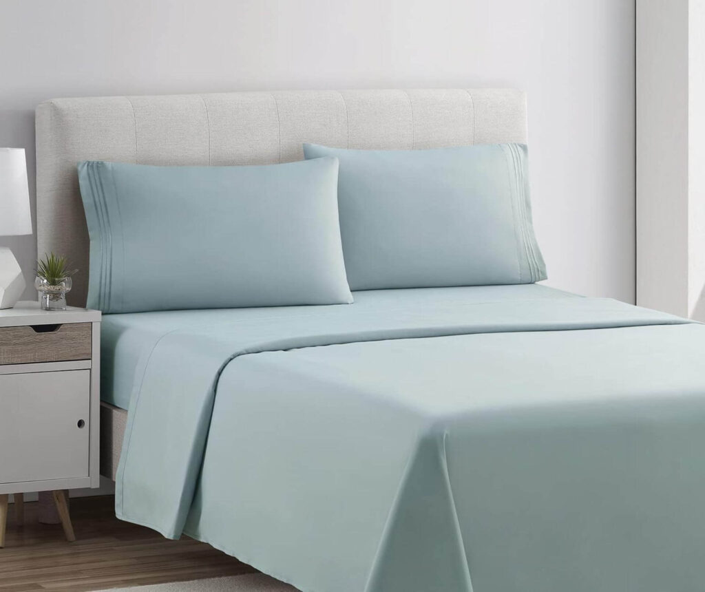 Cama impecablemente tendida con un elegante juego de cama de color verde, creando un ambiente fresco y sereno en el dormitorio