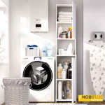 Mueble columna auxiliar de lavandería blanco con puertas abiertas mostrando ropa de hogar y productos de limpieza en un lavadero iluminado.
