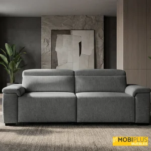 Sofá de 3 plazas tapizado en tela gris en salón de diseño sobrio con panel de piedra y planta, de MobiPlus Muebles.
