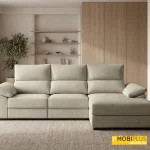 Texto Alt: Sofá chaise longue de tres plazas tapizado en tela beige o crema colocado en un salón moderno de estilo orgánico con muebles de madera.
