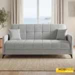 Sofá cama clic clac modelo Hawaii tapizado en tela de color gris claro en un salón luminoso.