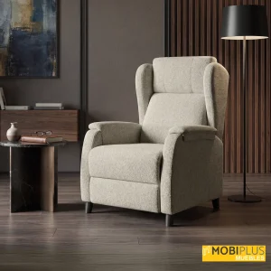 Sillón relax Royale beige en salón elegante con pared oscura, mesa de mármol y lámpara de pie.