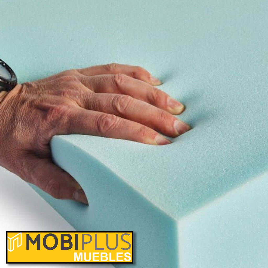 Mano comprobando la firmeza y densidad de un bloque de espuma para tipos de colchones en Mobiplus Muebles.